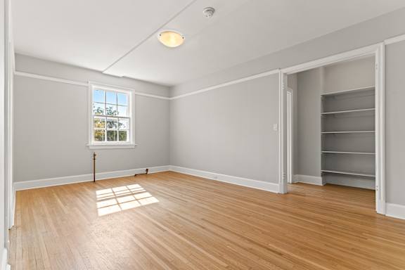 A room with a window and a wooden floor.