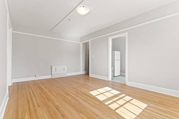 A room with wooden floors and a light switch on the wall.