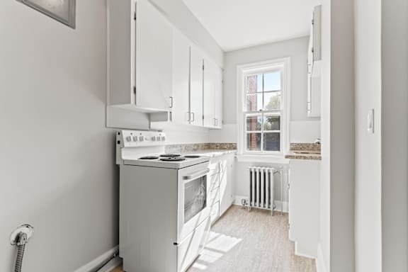 A kitchen with white cabinets and a stove top oven.