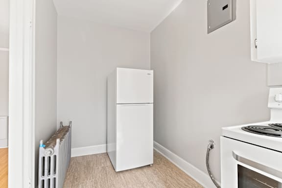 A white refrigerator is in a kitchen next to a white stove.
