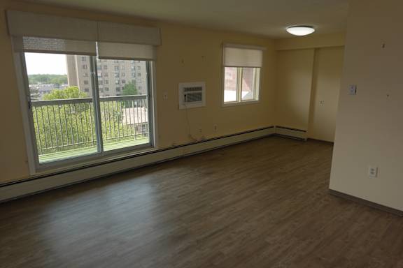 A room with a window overlooking a balcony with a railing.