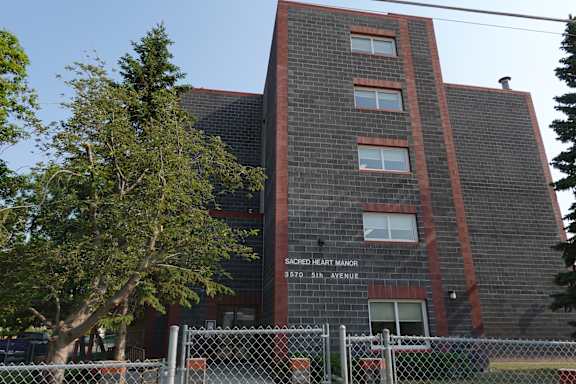 A brick building with a sign that says Sacred Heart Manor.