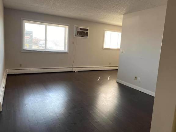 A room with a window and a vent on the wall.