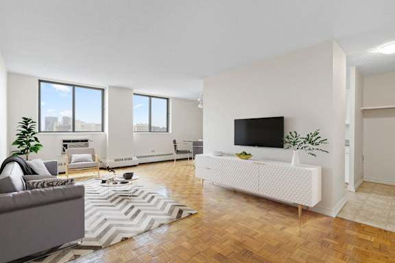 A living room with a grey couch, a white sofa, a television, and a plant.