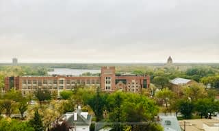A large brick building sits in the middle of a green field.