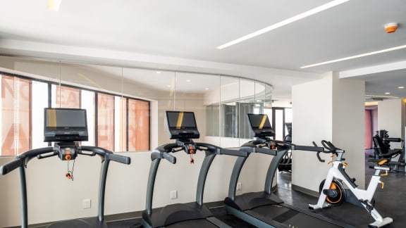 four treadmills in a gym with a wall of windows