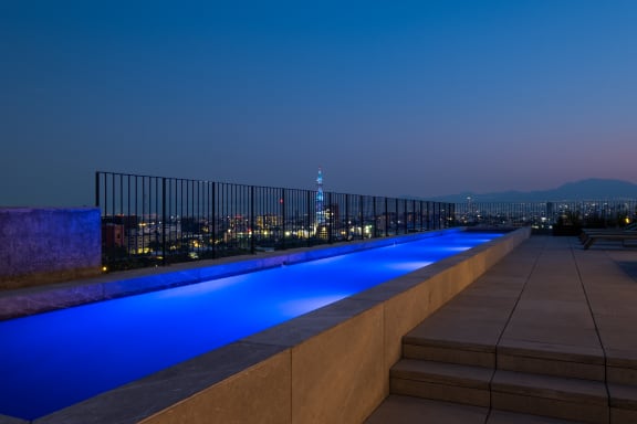 a rooftop pool with the empire state building in the background at night