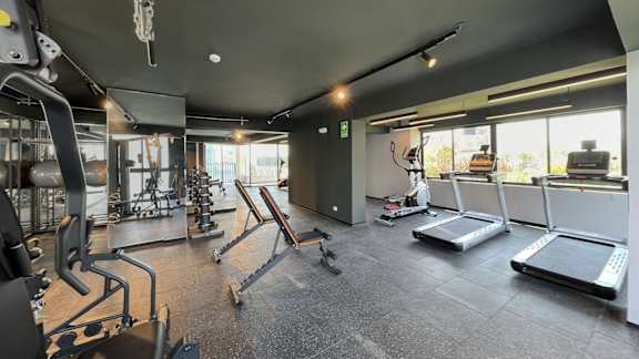 A gym with a variety of equipment including treadmills, weights, and exercise machines.