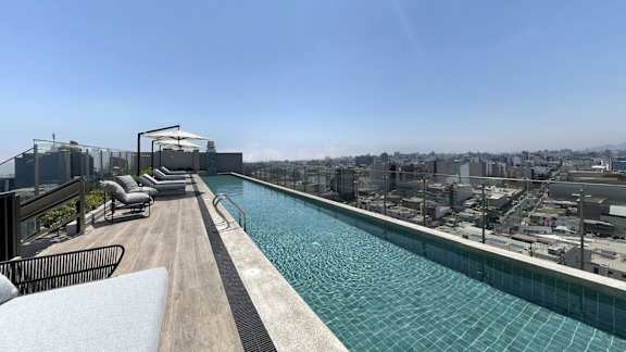 A long rectangular pool with a wooden deck and lounge chairs.