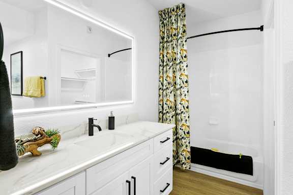 A bathroom with a white countertop and a yellow and black shower curtain.