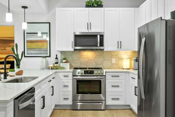 A modern kitchen with white cabinets and stainless steel appliances.