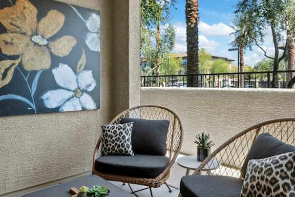 Two wicker chairs with cushions are placed on a patio.