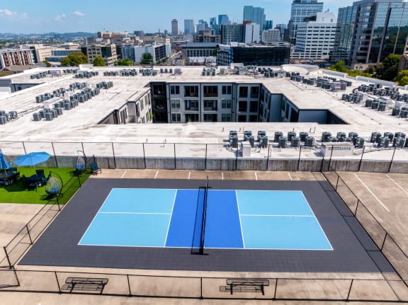 an aerial view of two blue tennis courts on top of a building with a city