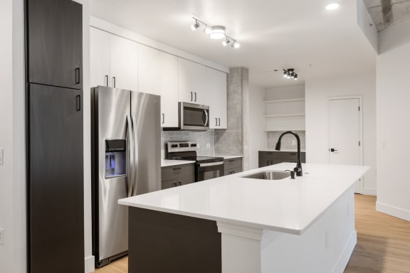 a large white kitchen with stainless steel appliances and a white counter top