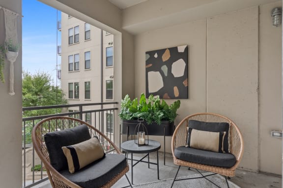 a balcony with two chairs and a table and a painting on the wall