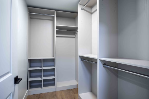 a walk in closet with white walls and shelves