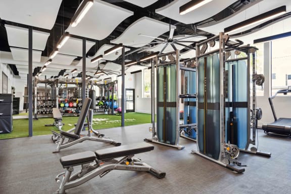a spacious fitness center with exercise equipment and a grassy area in the background