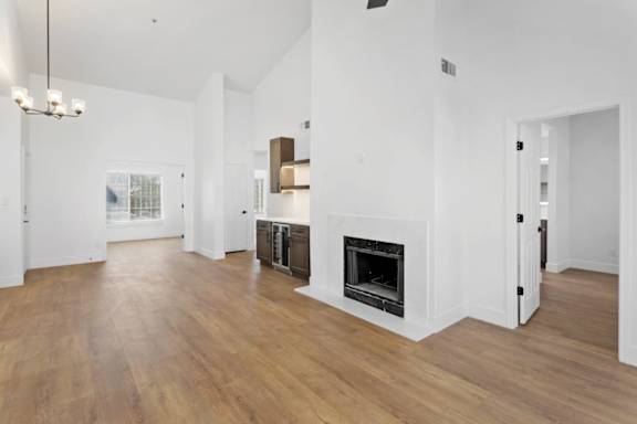 A large, empty room with a fireplace and wooden floors.