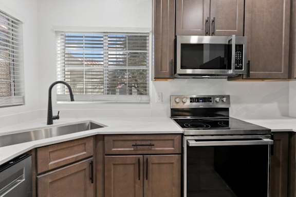 A kitchen with brown cabinets and a stainless steel oven.