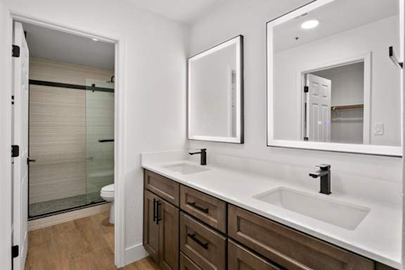 A bathroom with a sink, mirror, and a shower with a glass door.