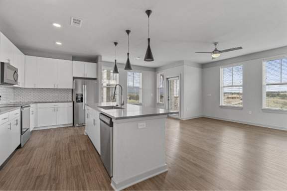 A modern kitchen with white cabinets and a wooden floor.