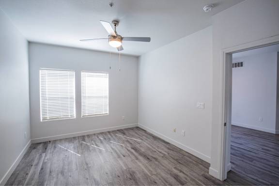 A room with a ceiling fan and wooden flooring.