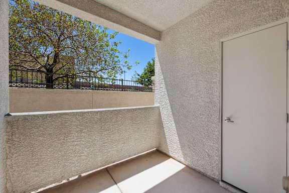 A balcony with a white door and a concrete wall.