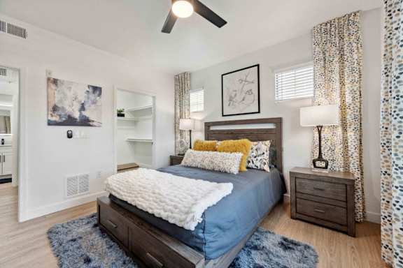 A bedroom with a bed, nightstand, and a ceiling fan.