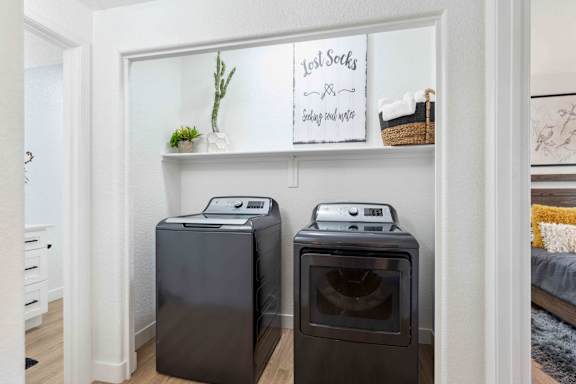 Two black front load washing machines in a laundry room.