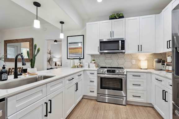A modern kitchen with white cabinets and stainless steel appliances.
