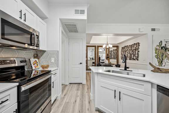A modern kitchen with white cabinets and a black stove top oven.