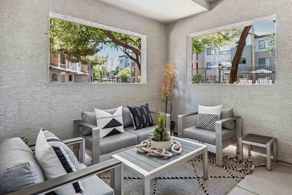 A modern living room with a glass table and grey couches.