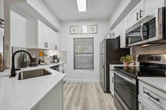 A modern kitchen with white cabinets and stainless steel appliances.