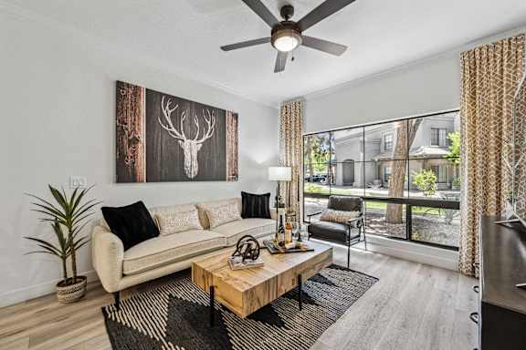 A living room with a white couch, a wooden coffee table, and a deer head on the wall.