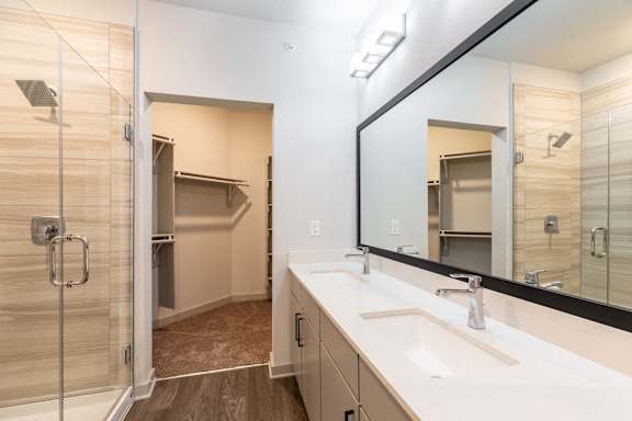 A bathroom with a walk-in shower and double sinks.