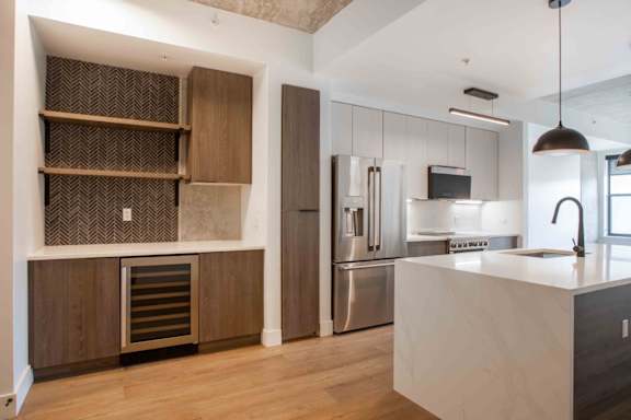 A modern kitchen with a white countertop and stainless steel appliances.