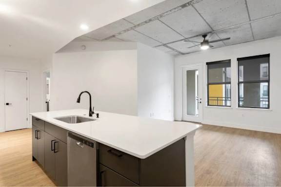 A kitchen with a white counter top and a sink.