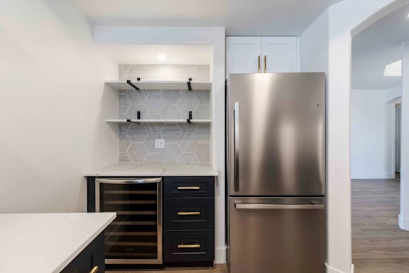 A modern kitchen with a stainless steel refrigerator and black drawers.