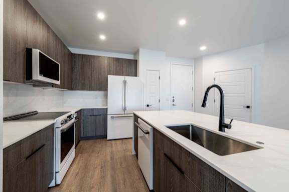 A modern kitchen with white countertops and dark wood cabinets.