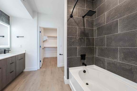 A modern bathroom with a white tub and a walk-in shower.