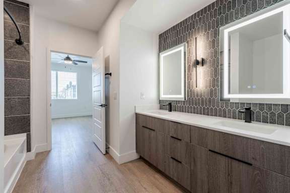 A bathroom with a dark wood floor and white walls.