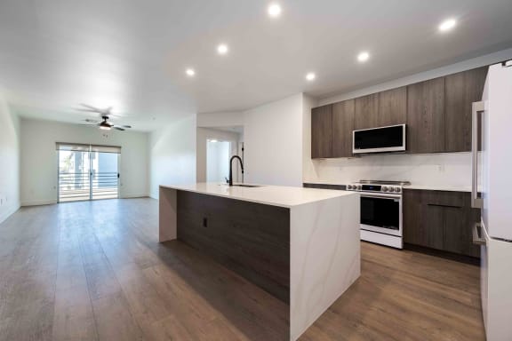 the kitchen has a large island with a white counter top and a stainless steel refrigerator