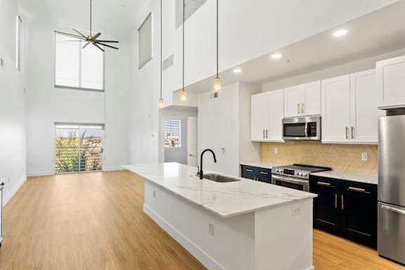 A modern kitchen with a white island and stainless steel appliances.