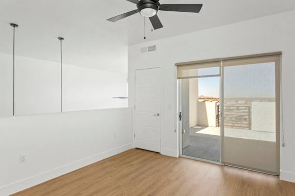 A room with a ceiling fan and sliding glass doors.
