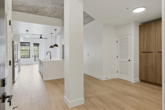 an open kitchen and living room with white walls and wood floors