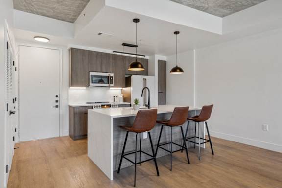 a kitchen with a large island with three bar stools