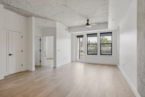 an empty living room with white walls and a ceiling fan
