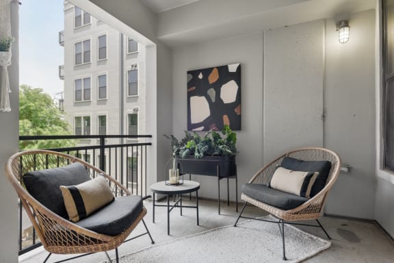 an apartment balcony with two chairs and a table and a potted plant