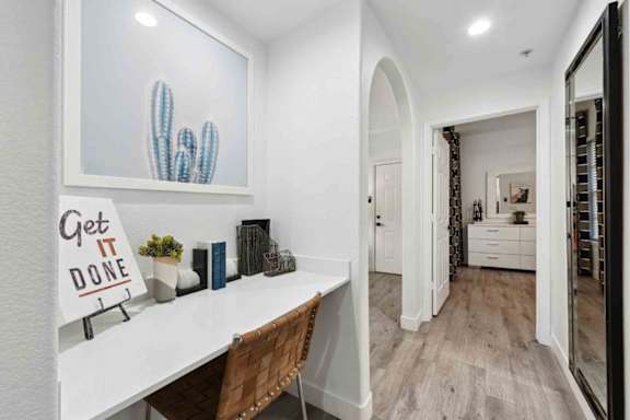 A white desk with a sign that says "Get it Done" sits in a room with a cactus and a mirror.