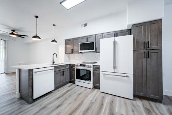 A modern kitchen with white appliances and dark wood cabinets.